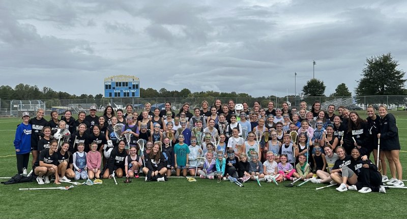 The UD women’s lacrosse team gathers on the Champions Stadium field with clinic attendees. SUBMITTED PHOTOS